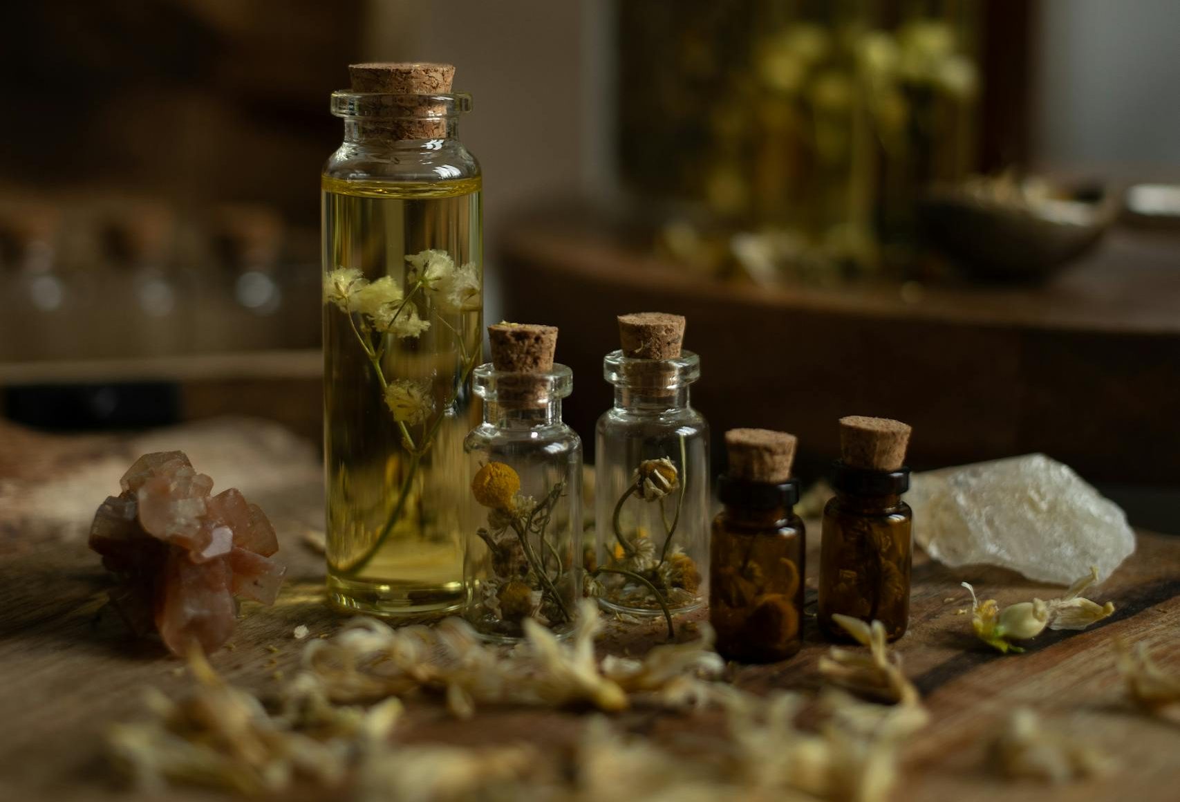 A collection of rustic glass bottles with aromatic herbs on a wooden table, perfect for aromatherapy themes.